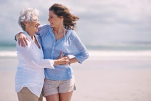 Older woman hugging her daughter on the beach