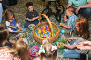 Children choosing Easter eggs from a large basket during a Welch Senior Living community event