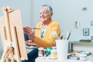 Senior woman in bright yellow sweater painting