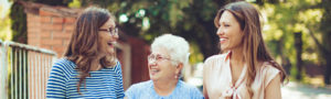 Older woman walking outdoors with her adult daughters