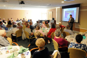 Presenter in front of a room of older adults learning about senior living