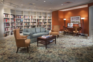 Comfortable sofa and chairs in front of a wall of books in a senior living community library