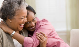 Older African-American woman laughing and hugging her daughter